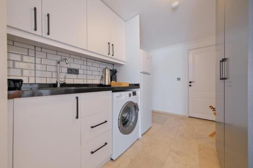 a kitchen with white cabinets and a washing machine at Körfez Residence in Fethiye