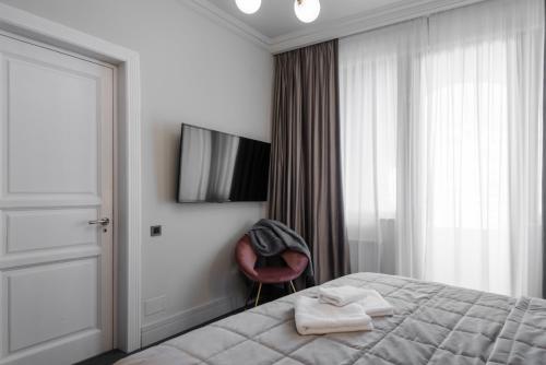 a bedroom with a bed and a television and a chair at HIGHLINE DOWNTOWN ApartHotel OLDTOWN UNIRII SQUARE in Bucharest