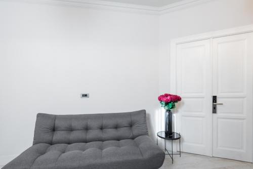 a couch in a living room with a vase of flowers at HIGHLINE DOWNTOWN ApartHotel OLDTOWN UNIRII SQUARE in Bucharest