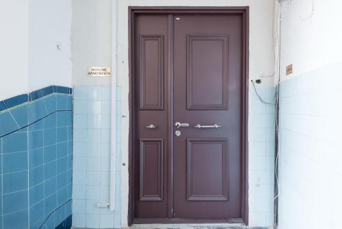a brown door in a hallway with blue tiles at HIGHLINE DOWNTOWN ApartHotel OLDTOWN UNIRII SQUARE in Bucharest