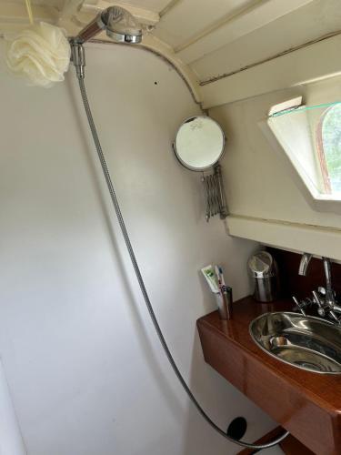 une salle de bain avec un lavabo et un miroir dans l'établissement Séjour insolite sur un bateau, à Louveciennes