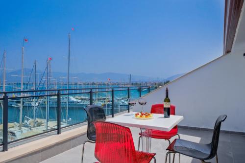 a table with a bottle of wine and chairs on a balcony at Körfez Residence in Fethiye