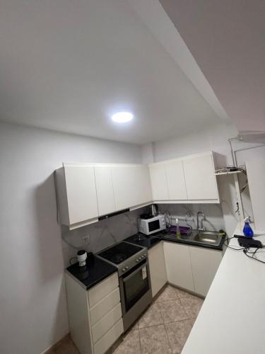 a small kitchen with white cabinets and a sink at Cozy Apartment in Sarandë