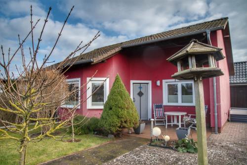 a red house with a bird feeder in front of it at Runddorf 1 in Mönkebude