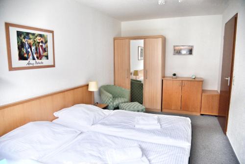 a bedroom with a white bed and a chair at Lagunenstadt am Haff Fewo 125 - Yarn in Ueckermünde