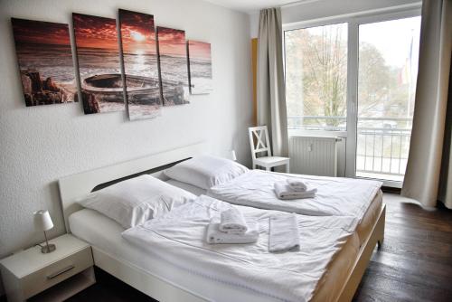 ウッカーミュンデにあるLagunenstadt am Haff Fewo 47 - Kehr wieder!の大きな窓のある部屋にある白いベッド