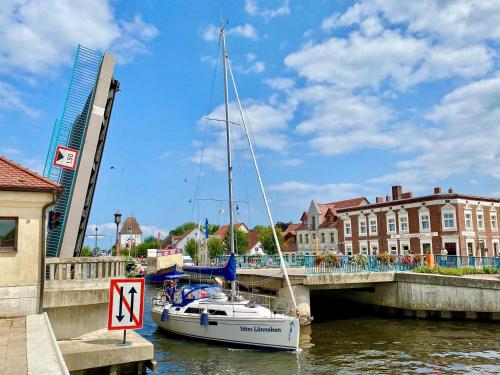 a sailboat is docked in the water near a bridge at Lagunenstadt am Haff Fewo 119 - Marina in Ueckermünde