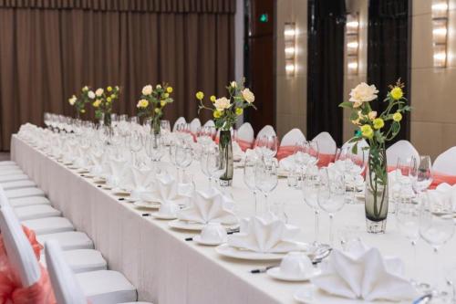 a long white table with glasses and flowers on it at YUN-RAY Hotel Shijiazhuang in Shijiazhuang