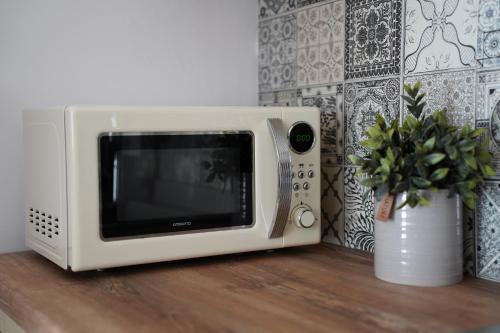 a white microwave sitting on a wooden table with a plant at Atlantis Atmosphere Apartment in Burgas City