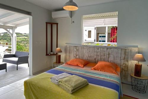 1 dormitorio con 1 cama con almohadas de color naranja y espejo en Ti sunset et bungalow 2 chambres, en Le Carbet