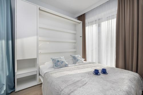 a bedroom with a white bed with blue glasses on it at Wellness Resort & SPA Dziwnów Apartments with Parking by Noclegi Renters in Dziwnów