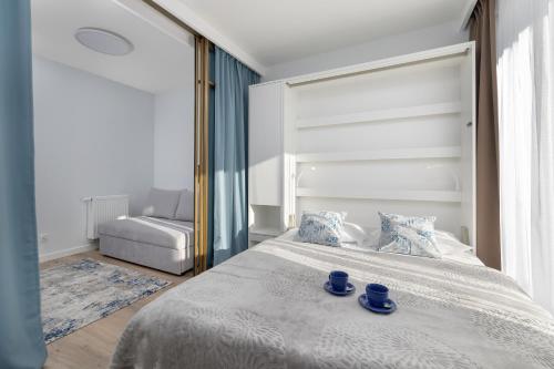 a bedroom with a bed with blue dishes on it at Wellness Resort & SPA Dziwnów Apartments with Parking by Noclegi Renters in Dziwnów