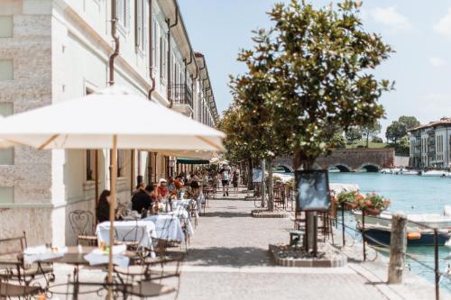 a group of people sitting at tables with an umbrella at Pavillon Suite in Peschiera del Garda