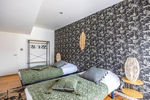 una camera da letto con due letti e una carta da parati in bianco e nero di OIQIA • Téralis • Estival ad Annonay