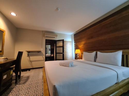 a bedroom with a large white bed and a desk at The 8 Factory Hotel Phitsanulok in Phitsanulok