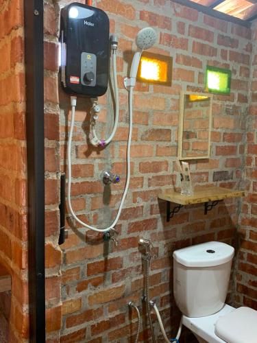 a bathroom with a toilet and a brick wall at Balam Inn Homestay & Chalet in Kampong Kebun Baharu