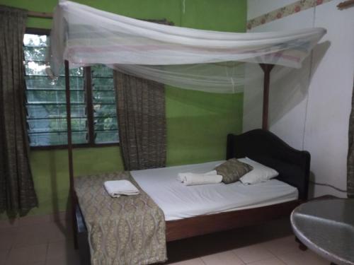 a bedroom with a bed with a canopy and a table at Fred Hunter Villa in Tiwi