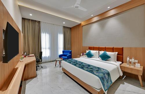 a hotel room with a bed and a flat screen tv at The Orchid Jamnagar in Jamnagar
