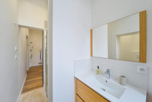 une salle de bain blanche avec un lavabo et un miroir dans l'établissement OIQIA • Échappée Belle, à Bourges