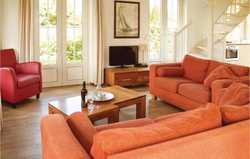 a living room with orange couches and a television at Tulp En Zee 6 Persoons in Noordwijk aan Zee