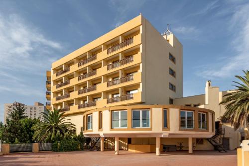 a large yellow building with palm trees in front of it at Parador de Melilla in Melilla