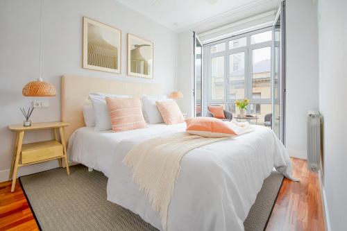 biała sypialnia z dużym białym łóżkiem z różowymi poduszkami w obiekcie San Sebastian City Center⎮3 Bedrooms⎮Free WIFI w mieście San Sebastián
