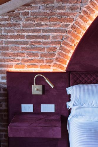 a bedroom with a bed and a brick wall at Pavillon Suite in Peschiera del Garda