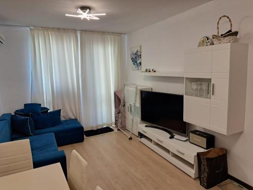 a living room with a blue couch and a tv at Domus Extra Apartments in Sveti Vlas