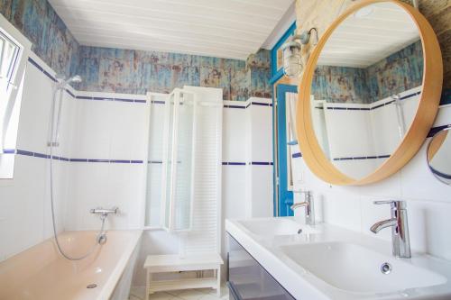 une salle de bain avec une baignoire, un lavabo et un miroir dans l'établissement La maison du pecheur, proche des plages, jardin, à Concarneau