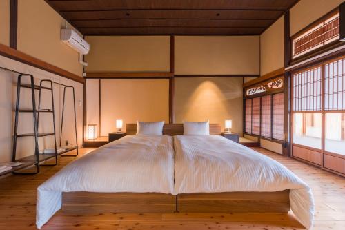 a large bed in a room with two windows at FARMSTAY miyuki-street "Hotaru" in Kugumiya