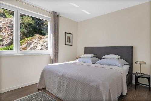 a white bedroom with a large bed and a window at Apartment Concha in Dugi Rat