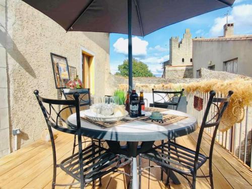 une table et des chaises sur un balcon avec un parasol dans l'établissement Le Rendez Vous - parking gratuit, à Carcassonne