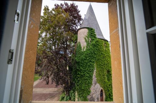 a view of a building covered in ivy through a door at Hôtel Château Schengen in Schengen