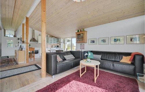 a living room with a black leather couch and a table at Holiday Home Ebeltoft 18 in Ebeltoft