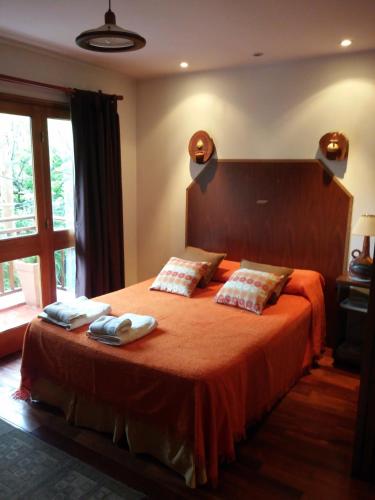 a bedroom with a large bed with orange sheets and pillows at Departamento Los Pinos in Salta