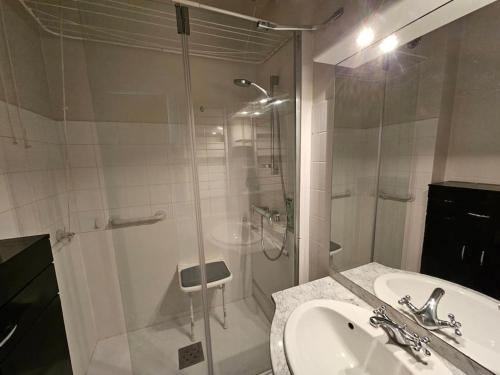 une salle de bain avec un lavabo et une douche en verre dans l'établissement L'idéal, appartement vue mer, à Étretat