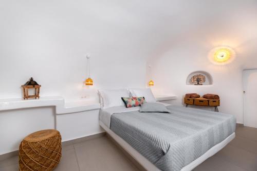 a white bedroom with a bed and a sink at Santorini Cave Suites Kontochori in Fira