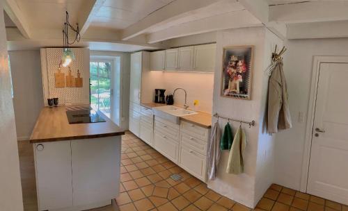 a kitchen with white cabinets and a sink at Mindedalen - Idyl tæt på alt og helt i fred in Billum