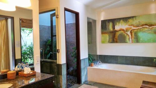 a bathroom with a tub and a painting on the wall at Villa Saraswati in Ubud