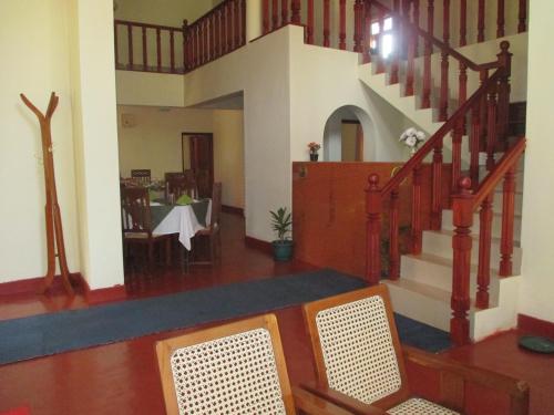a living room with a staircase and a dining room at Alfred Colonial Bungalow & Spice Garden in Kobbekaduwa