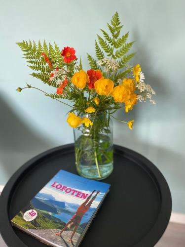 a vase with flowers and a book on a table at Lofoten Sea Lodge in Sennesvik