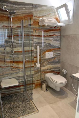 a bathroom with a toilet and a glass shower at B&B Primrose Residence Hotel in Rimini
