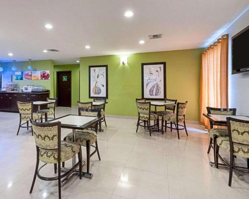 a restaurant with tables and chairs and green walls at Quality Suites in Sulphur