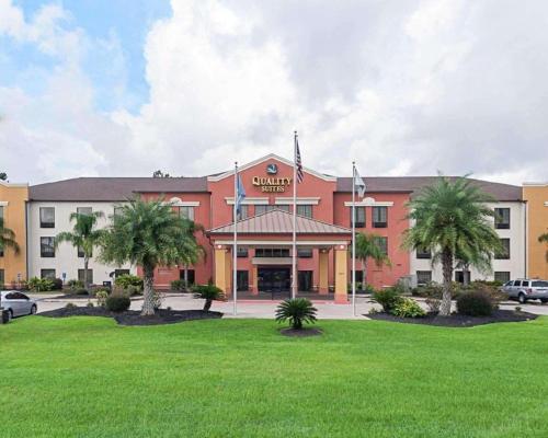a hotel with palm trees in front of a building at Quality Suites in Sulphur