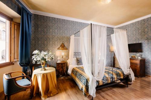 a bedroom with a bed with curtains and a table at Hotel Palazzo dal Borgo in Florence