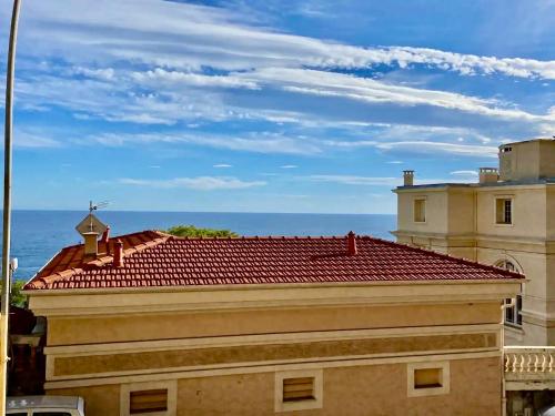 a building with a red roof with the ocean in the background at Comfortable 1-Bedroom Apartment Near Monaco in Roquebrune-Cap-Martin