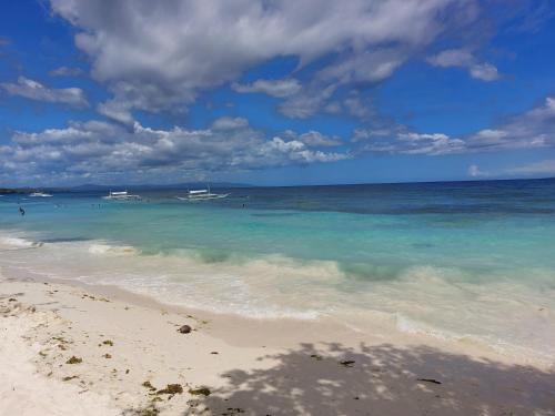 a beach with blue water and boats in the ocean at Yuken Mari Beach Resort Panglao in Panglao