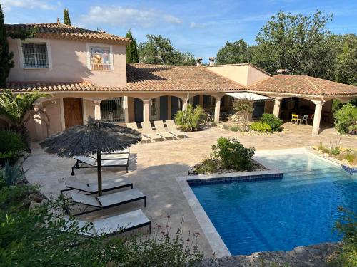 une maison avec une piscine et un parasol dans l'établissement L'Estancia, à Vézénobres
