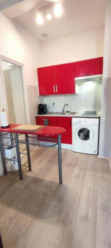 une cuisine avec des placards rouges, une table et un lave-linge dans l'établissement Coeur de Ville-Idéal Long Séjour-Bureau-Fibre, à Pau