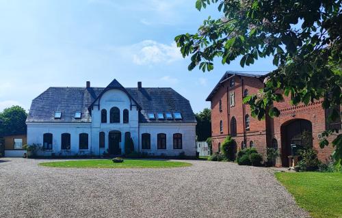 a large white building next to a brick building at Ferienwohnung auf dem Lande in Niesgrau